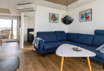 Soggiorno moderno in una casa vacanze a Hjørring, Danimarca con divano blu, quadri e vista sulla terrazza.
