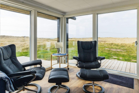 Zona lounge moderna in una casa vacanze a Hjørring, Danimarca, con grandi finestre e vista panoramica.