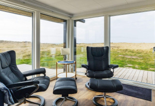 Zona lounge moderna in una casa vacanze a Hjørring, Danimarca, con grandi finestre e vista panoramica.