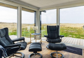 Zona lounge moderna in una casa vacanze a Hjørring, Danimarca, con grandi finestre e vista panoramica.