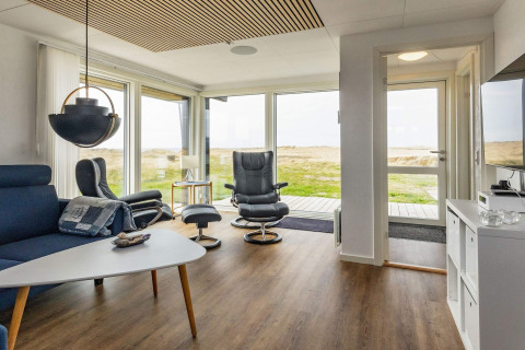 Lichte woonkamer met modern interieur en grote ramen in vakantiehuis in Hjørring, Denemarken.