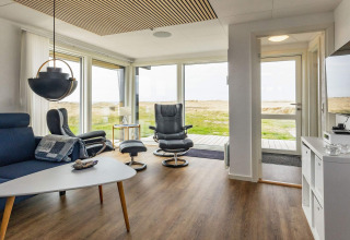 Soggiorno luminoso con arredi moderni e grandi finestre in una casa vacanza a Hjørring, Danimarca.