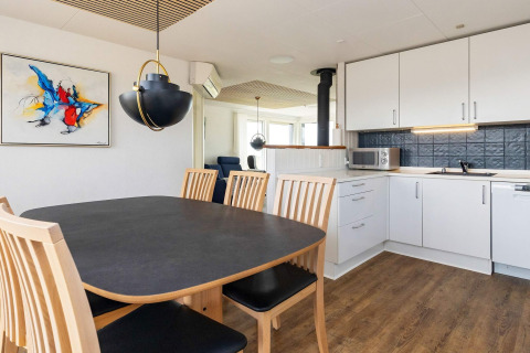 Modern dining and kitchen area at 7 person holiday home in Hjørring, Denmark, with light wood and art.