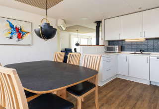 Modern dining and kitchen area at 7 person holiday home in Hjørring, Denmark, with light wood and art.