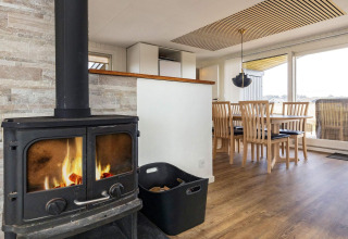 Gezellige woonkamer met houtkachel en eetruimte in een vakantiehuis in Hjørring, Denemarken.