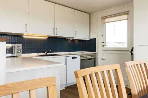 Moderne køkken i feriebolig i Hjørring, Danmark, med hvide skabe, blå fliser og spisehjørne.