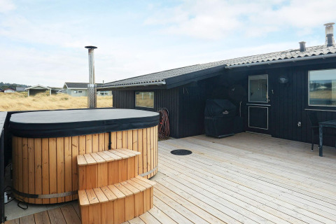 Træterrasse med et udendørs vildmarksbad og grill ved 7-personers feriehus i Hjørring, Danmark.
