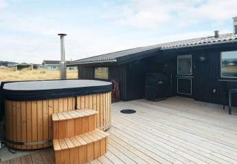 Houten terras met bubbelbad en barbecue bij het vakantiehuis voor 7 personen in Hjørring, Denemarken.