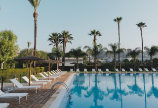 Grande piscine extérieure avec transats et palmiers au parc de vacances Wecamp Jávea, Valence, Espagne.