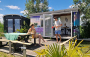 Twee mensen genieten buiten aan een kleurrijke tiny wagon bij Marina Parcs Almere in Nederland in de zomer.