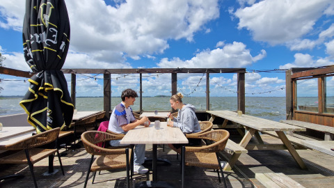 Zwei Personen sitzen an einem Tisch auf der Terrasse von Tiny Wagon Marina Parcs Almere in den Niederlanden.