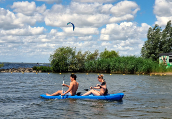Zwei Menschen paddeln in einem blauen Kajak am Tiny wagon, Marina Parcs Almere, Niederlande.