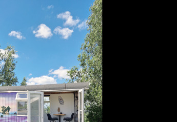 Foto della Tiny Wagon lodge a Marina Parcs Almere nei Paesi Bassi, sotto un cielo blu con nuvole.