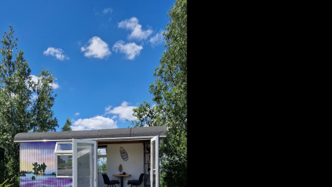 Billede af Tiny Wagon-lodgen ved Marina Parcs Almere i Holland under en klar blå himmel med skyer.