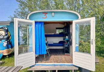 Tiny Wagon Lodge bei Marina Parcs Almere in den Niederlanden mit offenen Türen und Blick auf Etagenbetten.