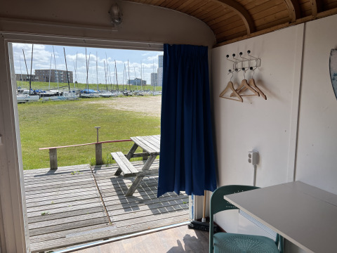 Vue depuis un Tiny Wagon à Marina Parcs Almere, Pays-Bas, montrant une table de pique-nique et des voiliers.