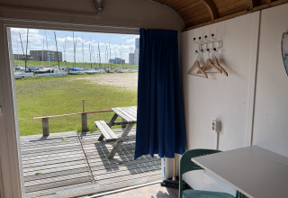 Vue depuis un Tiny Wagon à Marina Parcs Almere, Pays-Bas, montrant une table de pique-nique et des voiliers.