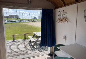 Vista desde un Tiny Wagon en Marina Parcs Almere, Países Bajos, con mesa de picnic y veleros afuera.