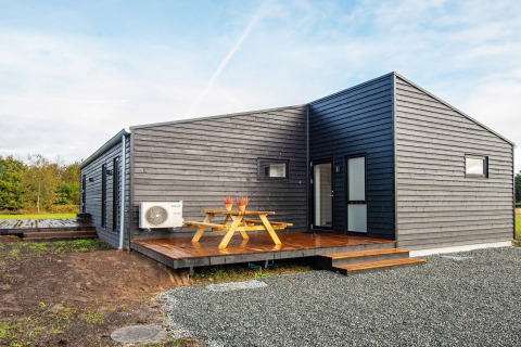 Modernes Ferienhaus für 8 Personen in Ansager mit Holzverkleidung, Terrasse und Sitzbank im Grünen.