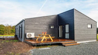 Casa vacanze moderna per 8 persone ad Ansager, con rivestimento nero, terrazza e tavolo da picnic fuori.