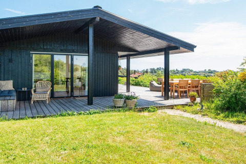 Zonnig terras met zitplaats bij 8-persoons vakantiehuis in Ebeltoft, omgeven door groen en uitzicht.