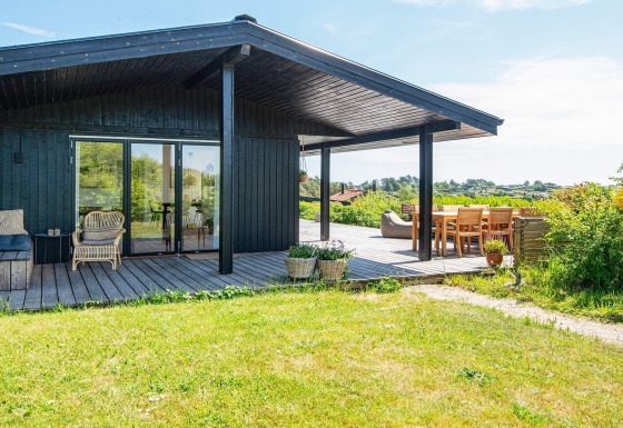 Terrasse ensoleillée avec coin salon à la maison de vacances 8 personnes à Ebeltoft, entourée de verdure.