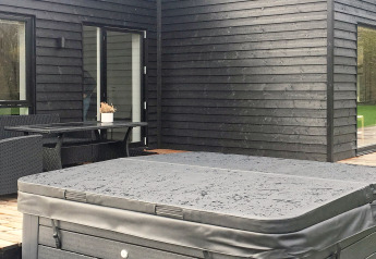 Espace extérieur d'une maison de vacances à Ansager, Danemark, avec jacuzzi couvert et bardage noir.