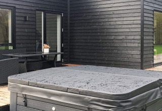 Area esterna di casa vacanze ad Ansager, Danimarca, con vasca idromassaggio coperta e rivestimento nero.