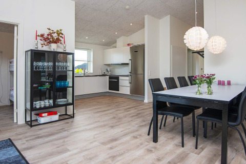Zona de comedor moderna y cocina en una casa de vacaciones en Ansager, Dinamarca, con suelo de madera clara.