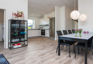 Zona de comedor moderna y cocina en una casa de vacaciones en Ansager, Dinamarca, con suelo de madera clara.