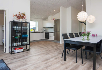 Zona de comedor moderna y cocina en una casa de vacaciones en Ansager, Dinamarca, con suelo de madera clara.