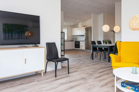 Heldere woonkamer in een vakantiehuis in Ansager, Denemarken; moderne meubels en open keuken op de achtergrond.
