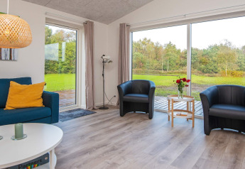 Salon lumineux dans une maison de vacances à Ansager, Danemark, avec grandes baies vitrées et vue sur la nature.