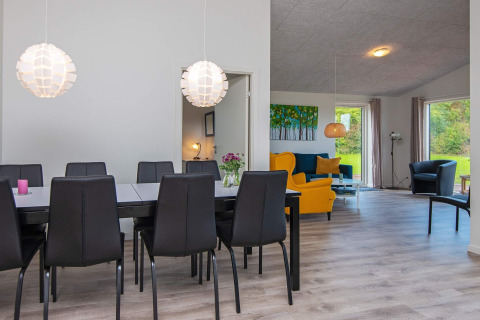 Moderne eet- en woonkamer met zwarte stoelen en kleurrijke fauteuils in een vakantiehuis in Ansager, Denemarken.