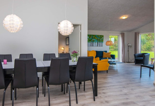 Salle à manger et salon modernes avec chaises noires et fauteuils colorés dans un gîte à Ansager, Danemark.