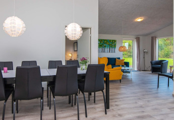 Moderne eet- en woonkamer met zwarte stoelen en kleurrijke zetels in een vakantiewoning in Ansager, Denemarken.