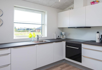 Cocina blanca moderna con ventana grande y electrodomésticos en casa vacacional para 8 personas en Ansager, Dinamarca.