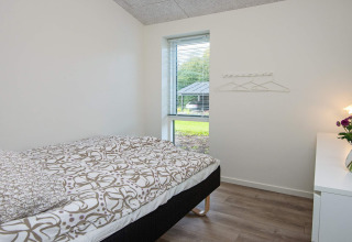 Chambre lumineuse et simple avec lit simple, déco moderne et vue sur le jardin à Ansager, Danemark.