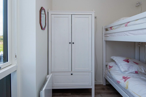 Dormitorio luminoso con litera, armario blanco y ventana en casa de vacaciones en Ansager, Dinamarca.