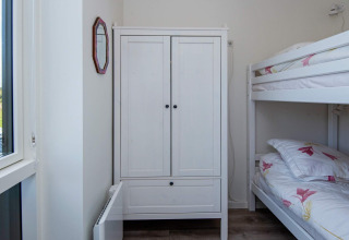 Helles Schlafzimmer mit Etagenbett, weißem Kleiderschrank und Fenster im Ferienhaus in Ansager, Dänemark.