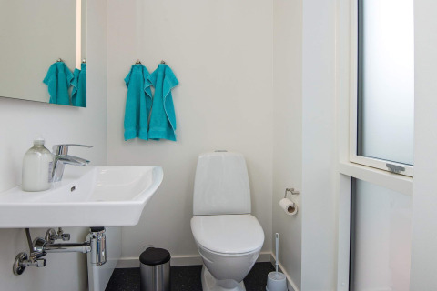 Salle de bain moderne dans une maison de vacances à Ansager, Danemark, avec toilette et serviettes bleues.