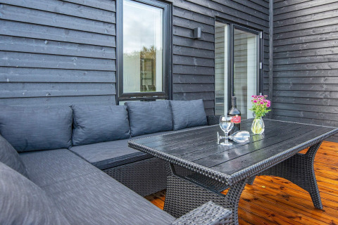 Buitenpatio bij 8-persoons vakantiehuis in Ansager, Denemarken, met zwarte bank en houten vloer.