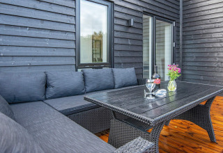 Terrasse des 8-Personen-Ferienhauses in Ansager, Dänemark, mit dunkler Sitzgruppe und Holzboden.