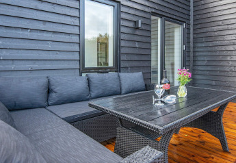 Buitenpatio bij 8-persoons vakantiehuis in Ansager, Denemarken, met zwarte bank en houten vloer.