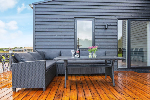 Buitenterras met zwart loungeset, tafel, wijn en bloemen bij 8 persoons vakantiehuis in Ansager, Denemarken.