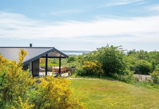 Casa de vacaciones moderna en Ebeltoft, Dinamarca, con terraza cubierta, jardín y vista al mar.
