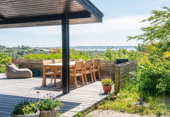 Zonnig terras bij het "8-persoons vakantiehuis in Ebeltoft" in Denemarken met zicht op de zee en natuur.