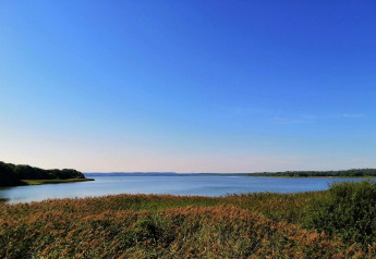 Udsigt over sø og natur fra 8-personers feriehus i Ebeltoft, Danmark, under en blå og klar himmel.