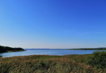Uitzicht op meer en natuur vanaf 8-persoons vakantiehuis in Ebeltoft, Denemarken, onder een blauwe lucht.