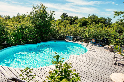 Piscine extérieure avec terrasse en bois entourée de verdure au gîte 8 personnes à Ebeltoft, Danemark.